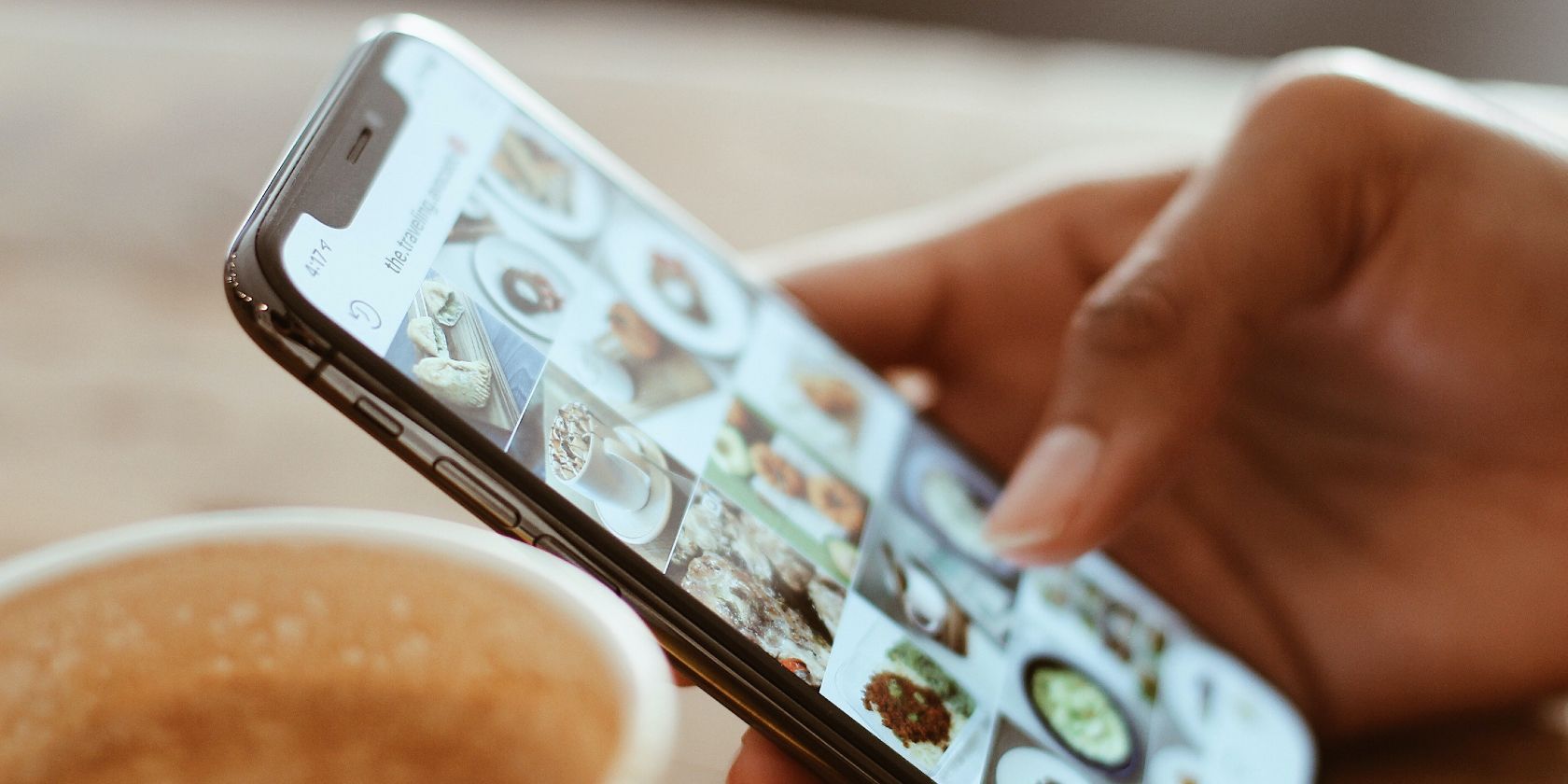 Photo of a person scrolling through Instagram next to a cup of coffee